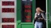 RUSSIA -- A woman leaves exchange office with an electronic panel displaying currency exchange rates for the U.S. dollar and the euro against the Russian ruble in Moscow, August 23, 2018.