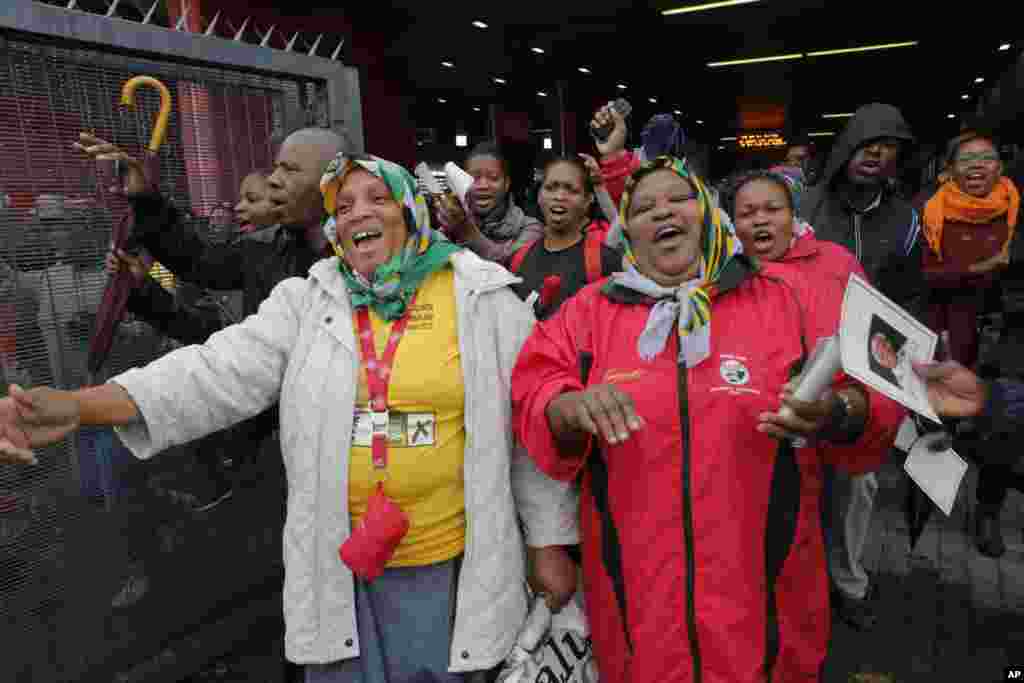 As pessoas dançam e cantam enquanto entram para o Estádio para participar na cerimónia fúnebre em honra a Nelson Mandela, no Soweto, junto a Joanesburgo, Dez. 10, 2013.