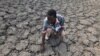 FILE - Last Zimaniwa feels the broken ground at a spot which is usually a reliable water source that has dried up due to lack of rains in the village of Chivi , Zimbabwe, Jan. 29, 2016. Southern Africa's lengthy drought has gotten worse, aid officials say