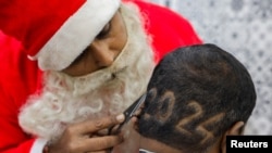 2023年12月31日，在印度艾哈邁達巴德的一家理髮店裡，一名理髮師身穿聖誕老人服裝，為客戶剪“2024”鬍鬚，迎接新年。（路透社）