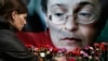 Seorang perempuan tampak meletakkan bunga di depan foto jurnalis Anna Politkovskaya, di Moskow, pada 7 Oktober 2009. Politkovskaya tewas dibunuh karena liputannya yang kritis terhadap Kremlin. (Foto: AP/Pavel Golovkin)