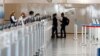 An American Airlines ticketing agent helps a woman as she approaches the counter in Denver International Airport as travelers deal with the effects of the new coronavirus, June 10, 2020, in Denver. 
