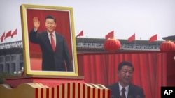 FILE - Participants cheer beneath a large portrait of Chinese President Xi Jinping during a parade to commemorate the 70th anniversary of the founding of Communist China in Beijing, Oct. 1, 2019.