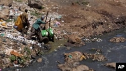 FILE - Workers dump effluent from pit latrines from the Korogocho slum of Nairobi, Kenya into a local water course.