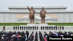 Attendees wearing face masks participate in an oath-taking meeting on Mansu Hill in Pyongyang