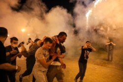 FILE - Protesters carry a wounded man during clashes with police after the presidential election in Minsk, Belarus, Aug. 10, 2020. A wave of COVID-19 has spread through Belarusian jails packed with people imprisoned for taking part in protests.