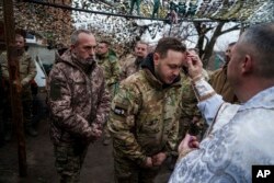 Vojni kapelan Jurij iz 24. mehanizovane brigade blagosilja ukrajinske vojnike tokom Božića u blizini grada Časiv Jar, Donjecka oblast, Ukrajina, sreda 25. decembra 2024. (AP foto/Evgenij Maloletka)
