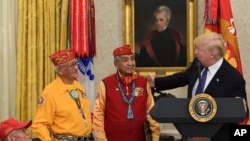 President Donald Trump, right, speaks about Sen. Elizabeth Warren, D-Mass., during a meeting with Navajo Code Talkers including, from left, Fleming Begaye Sr., Thomas Begay, and Peter MacDonald, in the Oval Office of the White House in Washington, Monday,