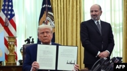အမေရိကန်သမ္မတ Donald Trump ကအိမ်ဖြူတော် ဘဲဥပုံရုံးခန်းမှာ အမြတ်ခွန်ကောက်ခံတဲ့အစီအစဥ် လက်မှတ်ထိုးပြီးတာကို ပြသနေစဥ်။ (ဖေဖော်ဝါရီ ၁၃၊ ၂၀၂၅) 