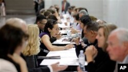 People have their resumes reviewed at a job fair