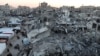 Palestinians walk among the rubble of buildings, In Khan Younis