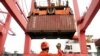 FILE - An employee guides as a crane unloads shipping containers from a cargo ship at a port in Lianyungang, Jiangsu province, China.