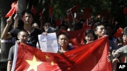 資料照片：2012年9月14日星期五，中國北京的反日抗議進入第四天，中國抗議者舉著中國國旗和寫著“日本狗，戰敗國”的紙遊行到日本大使館。