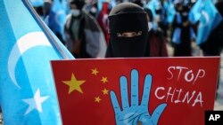 A protester from the Uyghur community living in Turkey holds up an anti-China placard during a protest against the visit of China's Foreign Minister Wang Yi to Turkey, in Istanbul, Thursday, March 25, 2021. (AP Photo/Emrah Gurel)