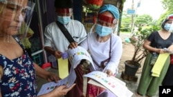 ရန်ကုန်မြို့ပြင် ရပ်ကွက်တခုတွင် ကြိုတင်မဲကောက်ယူနေသည့် ကော်မရှင် တာဝန်ရှိသူများနှင့် မဲဆန္ဒရှင်များ။ (အောက်တိုဘာ ၂၉၊ ၂၀၂၀)