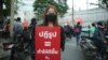 Baifern Benjama, a pro-democracy protester, holds a sign reading "Reform = make it better," at a Bangkok street protest. (Vijitra Duangdee/VOA)