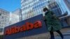 Seorang perempuan yang mengenakan masker berjalan melewati kantor perusahaan e-commerce asal China, Alibaba, di Beijing, pada 13 Desember 2021. (Foto: AP/Andy Wong)