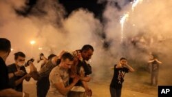 FILE - Protesters carry a man wounded during clashes with police after the presidential election in Minsk, Belarus, Aug. 10. Hundreds of people released from custody after a violent crackdown on protests in Belarus are sharing their accounts of harsh trea