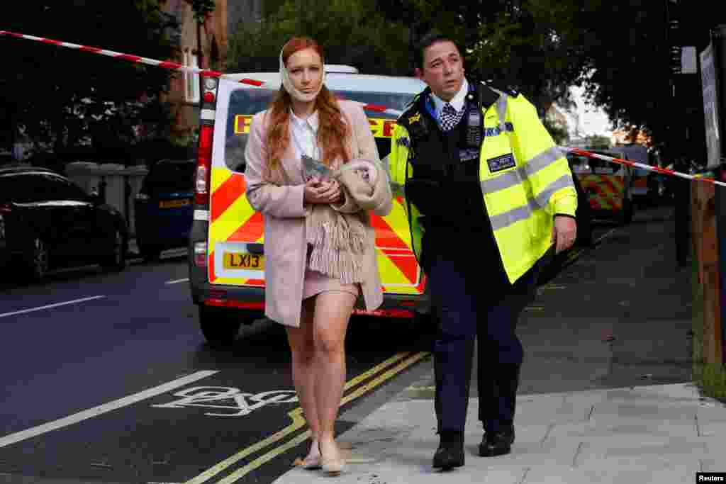 An injured woman is led away after an incident at Parsons Green underground station in London, Britain