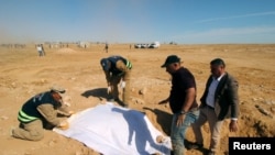 FILE - Iraqi members of the Civil Defense cover the bones from an unearthed mass grave of Kurds in west of the city of Samawah, Iraq, April 14, 2019.