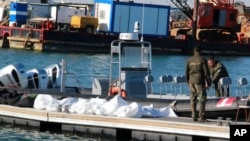 Arhiva - Pripadnici Obalne straže Tunisa stoje pored tela utpljenih migranata, u luci u Sfaksu, 24. decembra 2020.