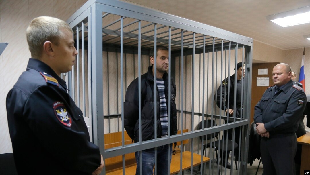 Police officers guards a cage with Greenpeace activist Ruslan Yakushev of Ukraine, Sept. 26, 2013. 