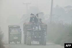 Para pekerja berkendara di jalan raya yang diselimuti kabut asap di pinggiran kota Lahore pada 6 November 2024. (Foto: AFP)
