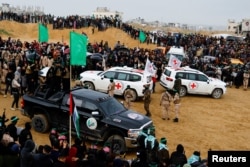Militan Palestina dan anggota Palang Merah berkumpul di dekat kendaraan saat Hamas menyerahkan sandera Israel yang telah meninggal kepada Palang Merah, di Khan Younis di Jalur Gaza selatan, 20 Februari 2025.