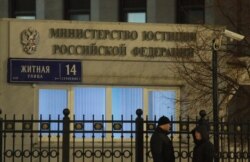 FILE - People stand outside Russia's Justice Ministry building, in Moscow, Russia Dec. 4, 2017.