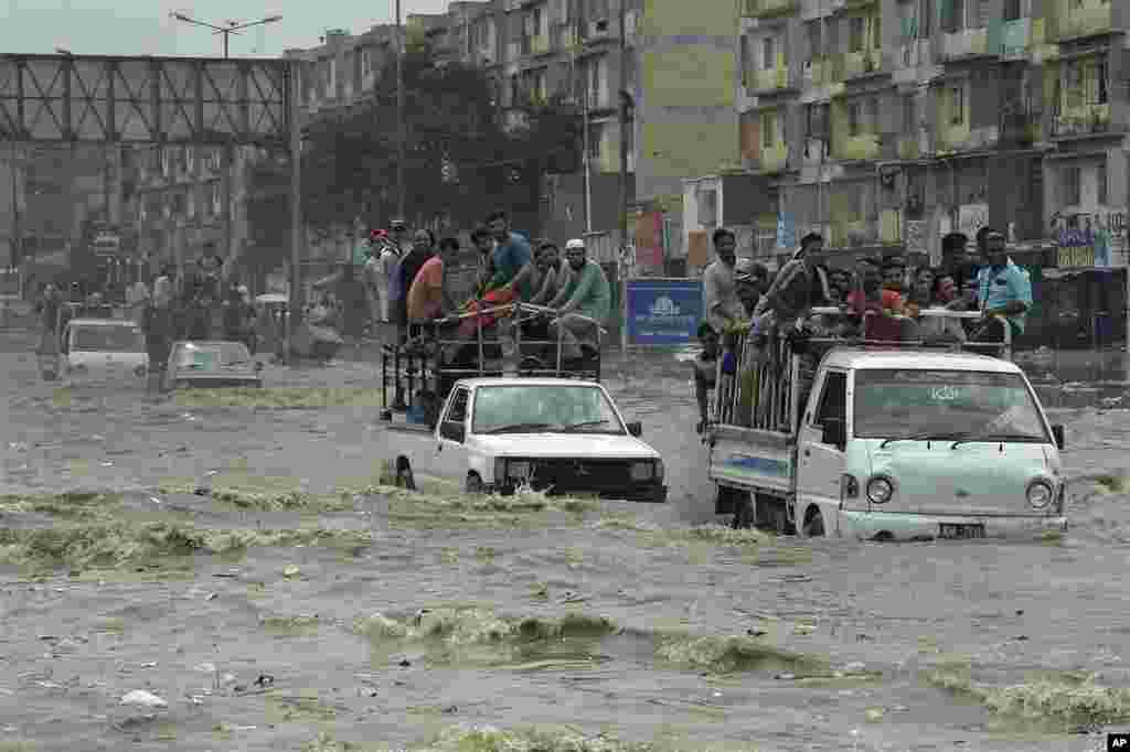 Pakistani commuters travel on a flooded street following a heavy rainfall in Karachi.