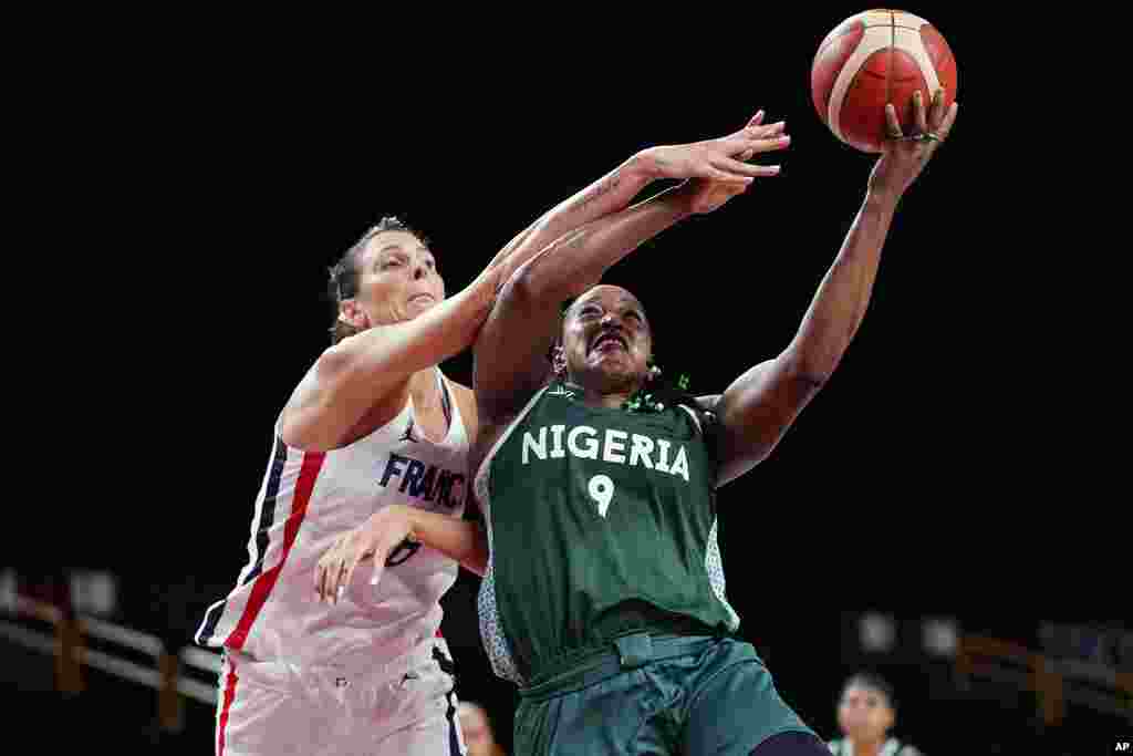 Nigeria's Aisha Mohammed (9) drives to the basket against France's Helena Ciak (8) during a women's basketball game at the 2020 Summer Olympics, Friday, July 30, 2021, in Saitama, Japan. (AP Photo/Eric Gay)