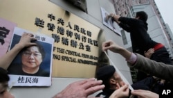  香港抗议者在北京驻香港机构中联办前贴上铜锣湾书店失踪老板 桂民海 的照片。 （2016年1月3日）