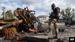 Seorang tentara Ukraina berdiri di dekat tank milik pasukan Rusia yang hancur di wilayah Kharkiv, Ukraina, pada 4 Oktober 2022. (Foto: AP/Andrii Marienko)