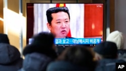 Ljudi gledaju TV program i fotografiju severnokorejskog idera Kim Džong Una, na železničkoj stanici u Seulu, Južna Koreja, 1. januara 2022.