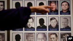 In this Thursday, Dec. 6, 2018 file photo, a sexual abuse victim points to the photos of Catholic priests accused of sexual misconduct by victims during a news conference in Orange, Calif.