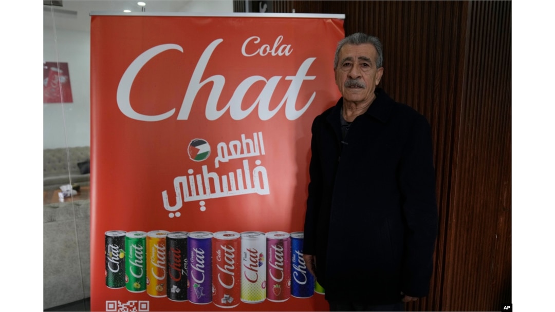 FILE - Fahed Arar, general manager of the Chat Cola Company poses next to an billboard with the company's brands that reads 'the Palestinian taste,' in the Palestinian company's bottling plant, in the West Bank city of Salfit, Feb. 13, 2025.