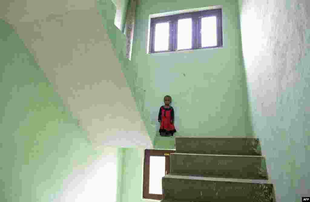 A Rohingya refugee child poses in the stairwell of a building on the outskirts of Srinagar on September 14, 2017.