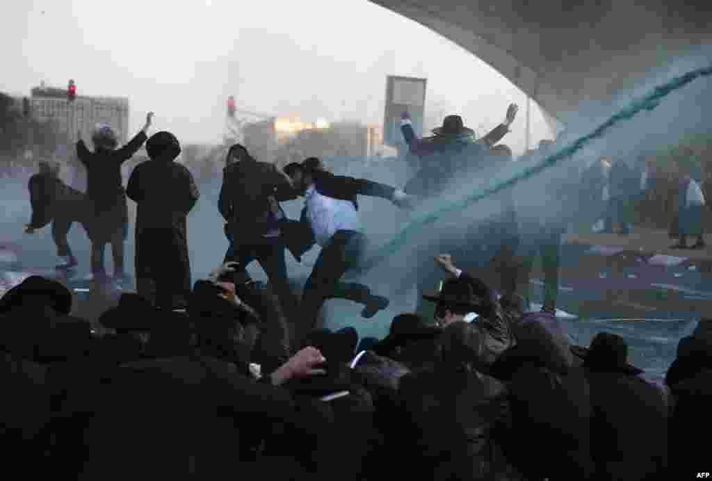 Members of the Israeli security forces use a foul-smelling spray known as "skunk" as they try to remove ultra-Orthodox Jews from blocking the road in a demonstration against Israeli army conscription in Jerusalem.