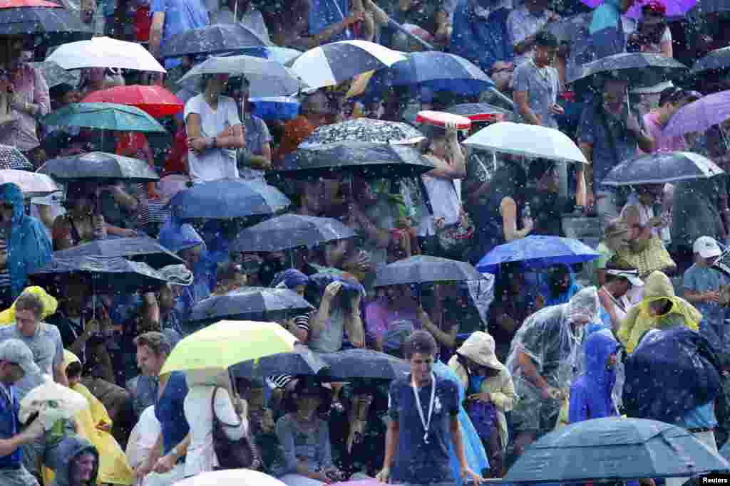 Spectators wait under their umbrellas as rain halts play at the U.S. Open tennis championships in New York.