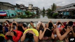 FILE - Filipino men place their hands over their heads as they are rounded up during a police operation in Manila on October 7, 2016, as part of the "War on Drugs" campaign by former Philippine President Rodrigo Duterte. (Aaron Favila/AP)