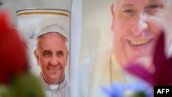 Bunga dan potret Paus Fransiskus diletakkan di patung Yohanes Paulus II di luar rumah sakit Gemelli tempat Paus Fransiskus dirawat, di Roma pada 24 Februari 2025. (Foto: AFP)