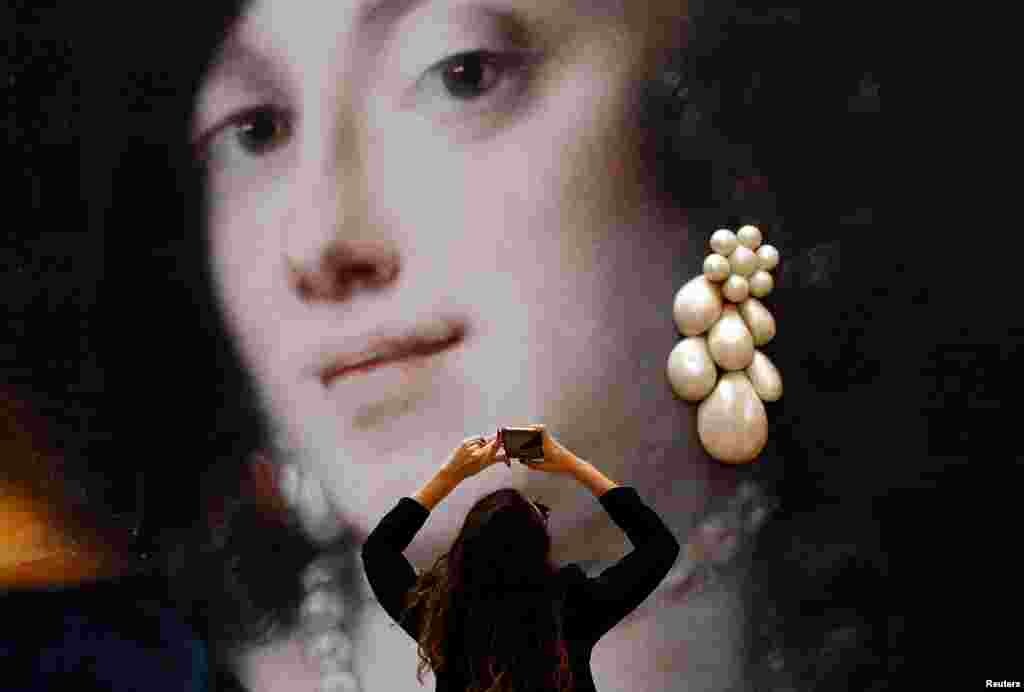 A woman takes a picture of an illustration which is a part of "Il Salotto Delle Gioie" exhibition in Milan, Italy.