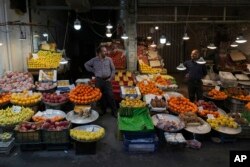 میوه فروشان در حالی که منتظر مشتریان در بازار محلی در تهران، ایران هستند، صحبت می کنند.