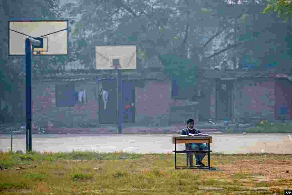 A school teacher conducts an online class near a basketball court at Swami Sivananda Memorial Institute in New Delhi. Keeping children at home and moving lessons online for days at a time during the peak of the smog crisis has become an annual ritual in the area. (Photo by Arun SANKAR / AFP)