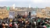 Palestinian Hamas fighters and people gather at the site of the handing over of the bodies of four Israeli hostages in Khan Yunis in the southern Gaza Strip on February 20, 2025.