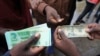 Zimbabweans compare the new note with the U.S. dollar note following the introduction of new notes by the Reserve Bank of Zimbabwe in Harare, Nov, 28, 2016. 