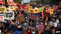 Protesters hold up signs during a demonstration outside the Myanmar Central Bank against the military coup in Yangon on February 16, 2021. (Photo by YE AUNG THU / AFP)