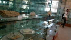FILE - An Afghan journalist walks by an exhibit of minerals on the way to a news conference by the Afghan Minister of Mines in Kabul, Afghanistan, June 17, 2010.