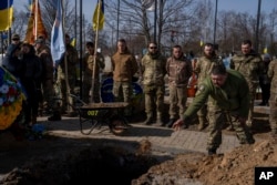 Ukrajinski vojnik baca zemlju u grob Jehora Vološina (27 godina), ukrajinskog vojnika, tokom pogrebne ceremonije u Pavlogradu, Dnjepropetrovska oblast, u Ukrajini, 26. februara 2024. Narednik 3. jurišne brigade poginuo je u borbama kod Avdejevke 21. februara 2024.