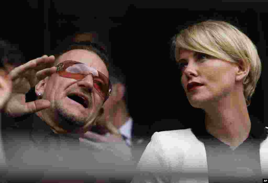 A actriz Charlize Theron fala com o músico Bono antes da cerimónia fúnebre oficial em memória a Nelson Mandela no Estádio FNB no Soweto junto a Joanesburgo, Dez. 10, 2013.